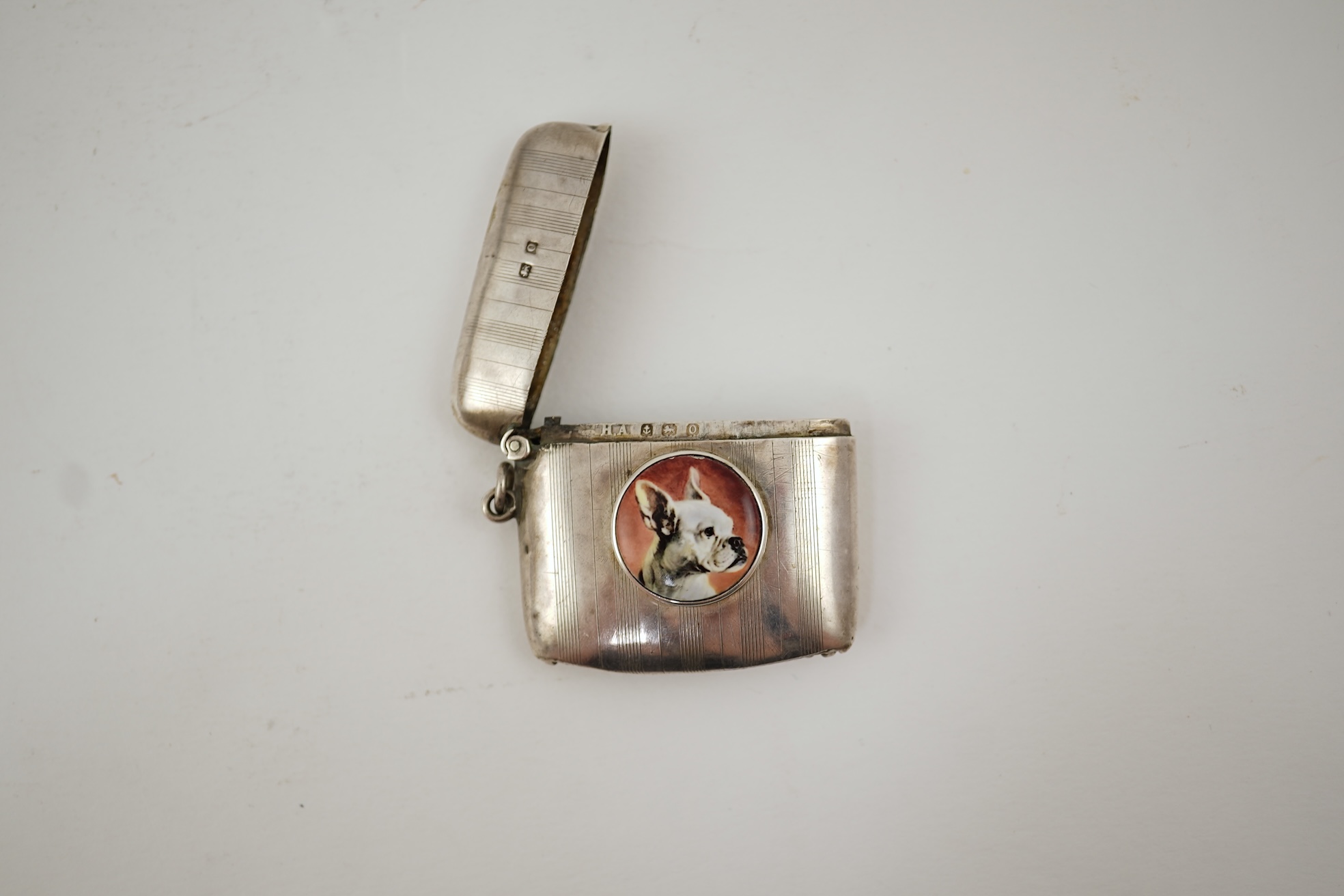 A George V silver and enamel vesta case, by Henry Hyde Aston, the inset circular enamel plaque decorated with a French bulldog
